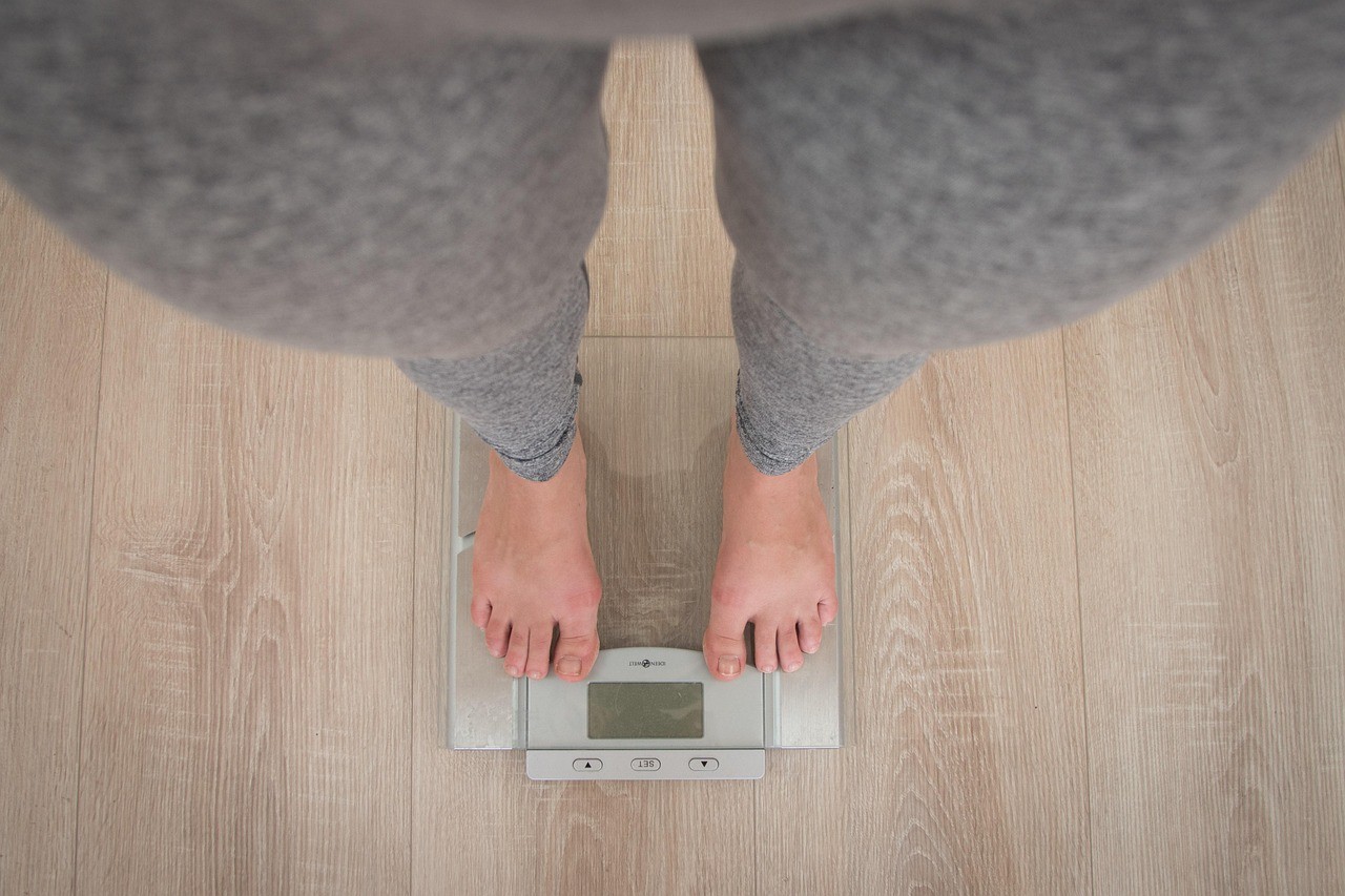 Person checking weight on a digital scale as part of a safe, natural metabolic weight loss journey.